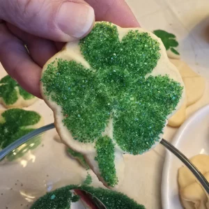 Sanding Sugar Decoration: Sprinkling sanding sugar onto a cookie with a corn syrup glaze.